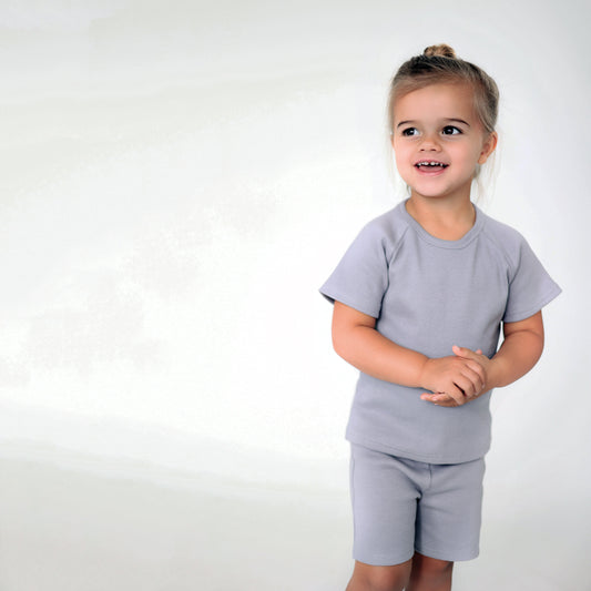 Child wearing a gray t-shirt and shorts set on a white background
