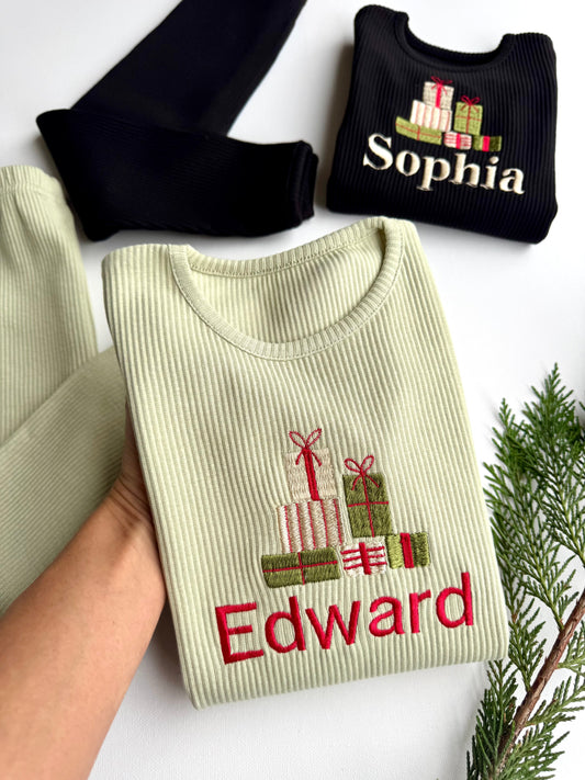 Two sweaters, one beige with 'Edward' and gift designs, the other black with 'Sophia', on a white background.